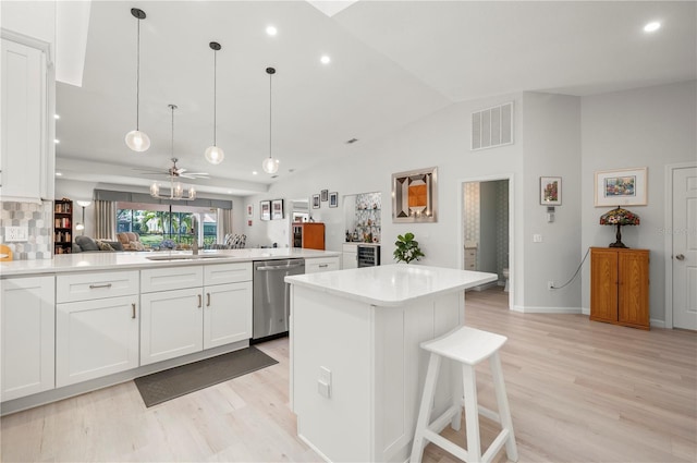 kitchen with tasteful backsplash, dishwasher, white cabinetry, pendant lighting, and a breakfast bar area