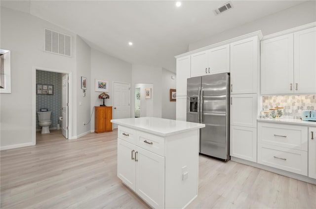 kitchen featuring light hardwood / wood-style floors, stainless steel fridge with ice dispenser, white cabinetry, a kitchen island, and vaulted ceiling