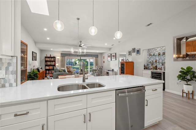 kitchen with sink, dishwasher, white cabinetry, and decorative light fixtures