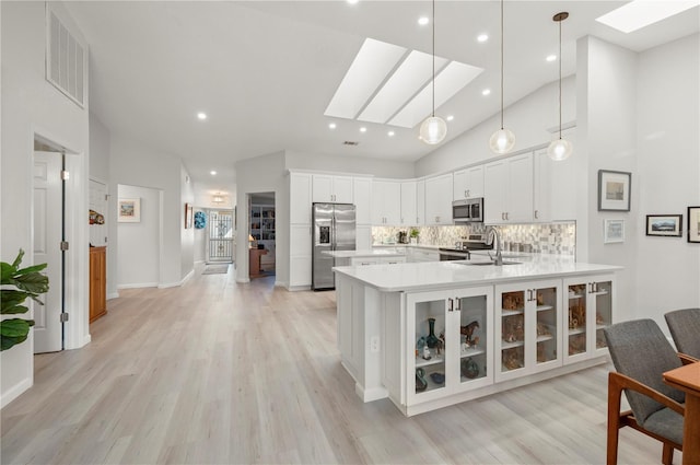 kitchen featuring stainless steel appliances, a skylight, white cabinetry, and kitchen peninsula