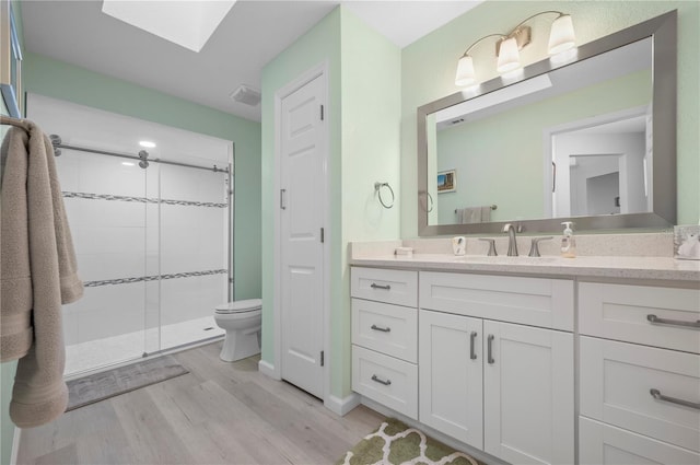 bathroom with an enclosed shower, vanity, a skylight, toilet, and hardwood / wood-style flooring