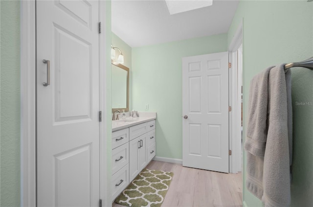 bathroom with hardwood / wood-style flooring, a skylight, and vanity