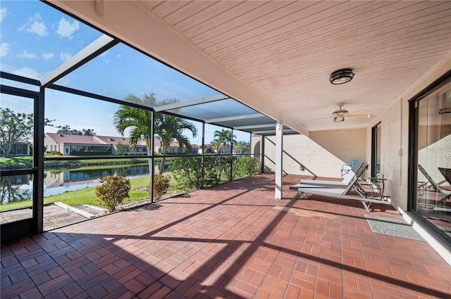 view of patio with glass enclosure, ceiling fan, and a water view