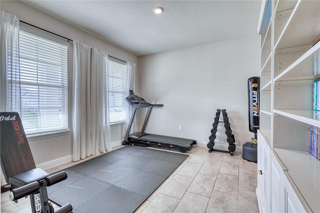 exercise room with a textured ceiling and light tile patterned flooring