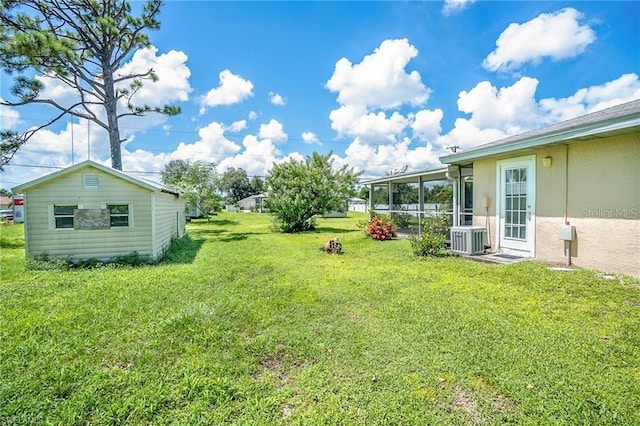 view of yard featuring an outbuilding, central air condition unit, and a sunroom