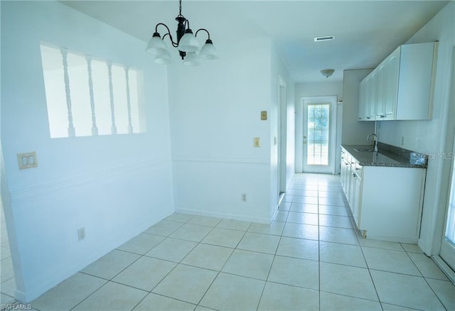 kitchen featuring sink, decorative light fixtures, white cabinetry, light tile patterned floors, and dark stone countertops