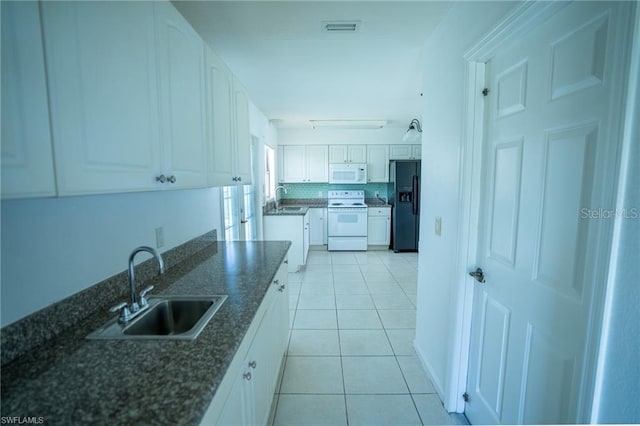 kitchen featuring white appliances, white cabinetry, dark stone countertops, sink, and light tile patterned floors