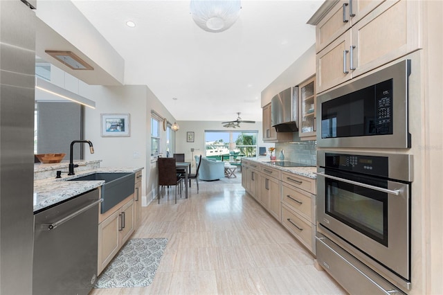 kitchen featuring appliances with stainless steel finishes, sink, decorative backsplash, light stone counters, and light brown cabinets