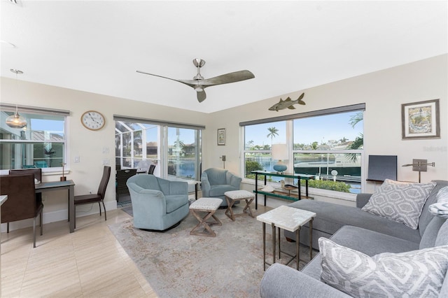 living room with tile patterned floors, ceiling fan, and a water view