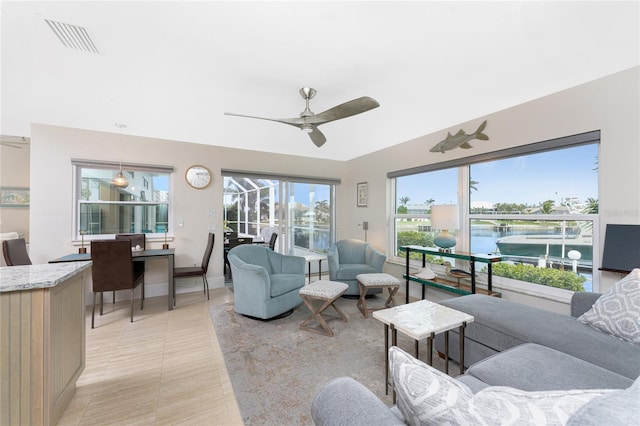 tiled living room with a water view and ceiling fan