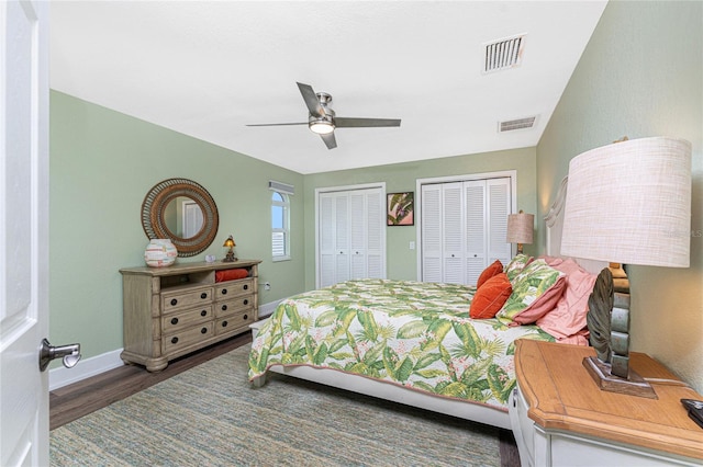 bedroom featuring multiple closets, ceiling fan, and dark hardwood / wood-style flooring