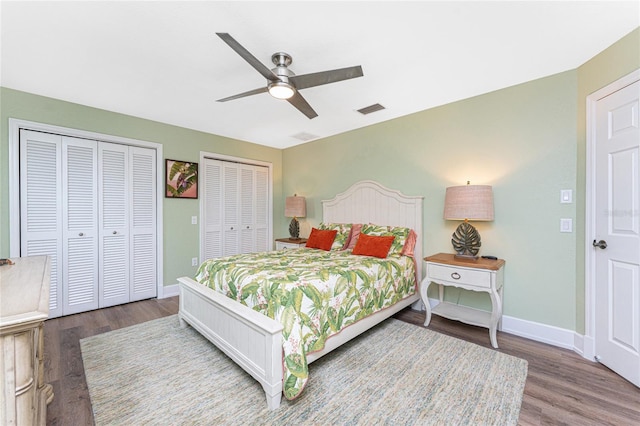 bedroom with wood-type flooring, two closets, and ceiling fan