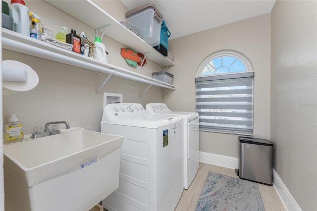 washroom featuring sink, washer and clothes dryer, and light hardwood / wood-style floors