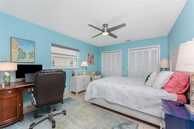 bedroom featuring multiple closets, ceiling fan, and light wood-type flooring