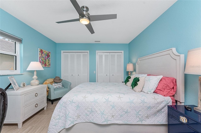 bedroom featuring multiple closets, light hardwood / wood-style floors, and ceiling fan