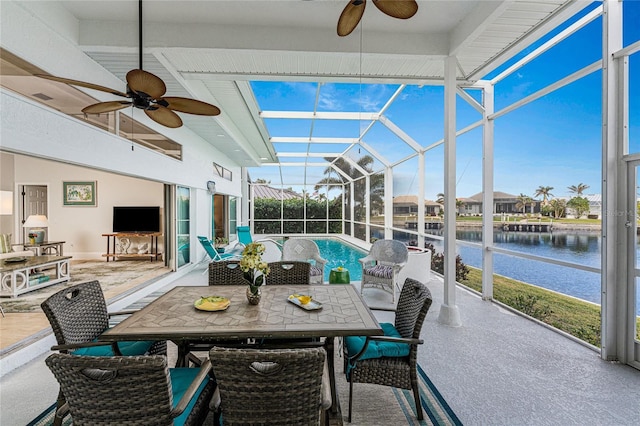 sunroom featuring beam ceiling, a water view, a wealth of natural light, and ceiling fan