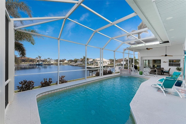 view of pool with a water view, ceiling fan, a patio, and glass enclosure