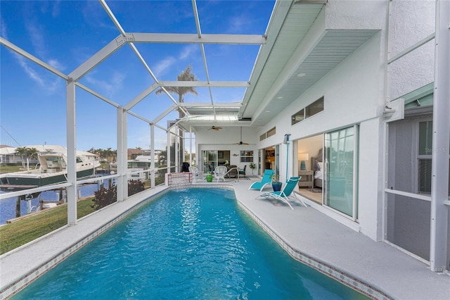 view of swimming pool featuring a patio, ceiling fan, and glass enclosure