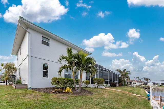 exterior space with a yard, a water view, and glass enclosure