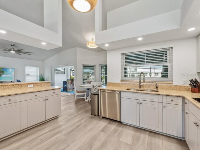 kitchen featuring light stone countertops, dishwasher, sink, white cabinets, and light wood-type flooring