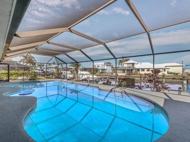 view of pool featuring glass enclosure and a water view