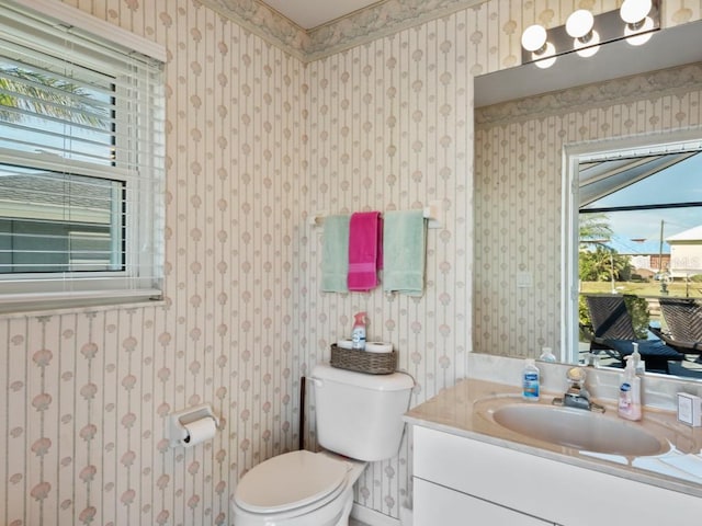 bathroom featuring toilet, vanity, and a healthy amount of sunlight