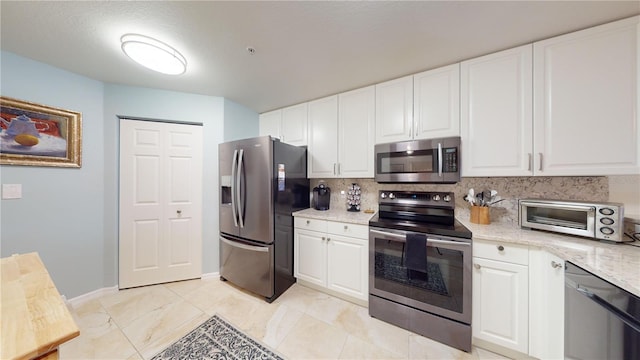 kitchen featuring light stone countertops, white cabinetry, appliances with stainless steel finishes, and decorative backsplash