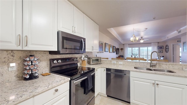 kitchen featuring white cabinets, stainless steel appliances, sink, backsplash, and a tray ceiling