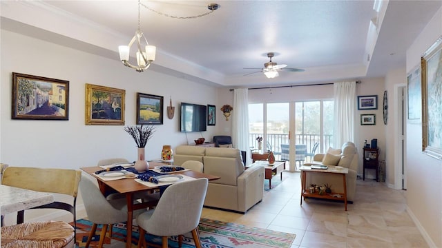 dining area with ceiling fan with notable chandelier, crown molding, and a raised ceiling