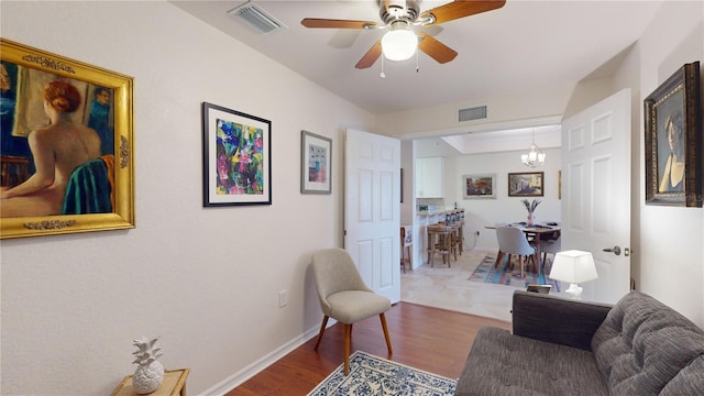 living room with hardwood / wood-style flooring and ceiling fan with notable chandelier