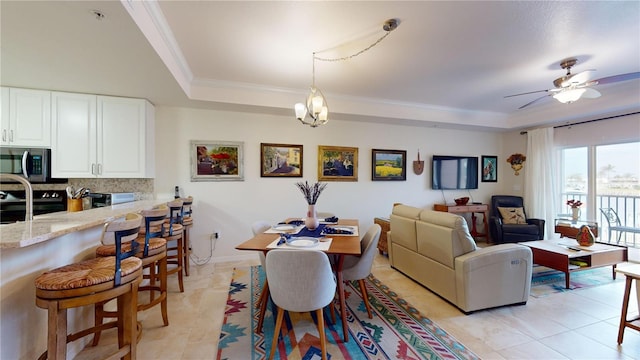 tiled living room featuring crown molding, ceiling fan with notable chandelier, and a raised ceiling