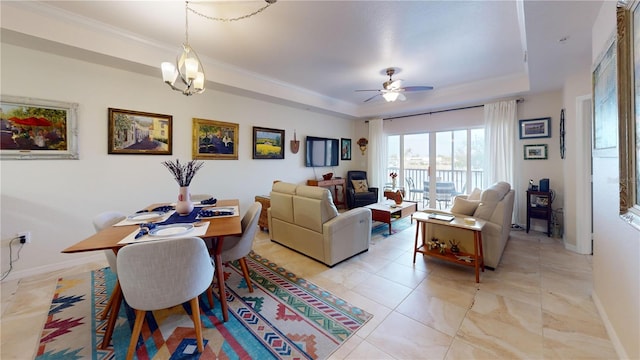 living room featuring ceiling fan with notable chandelier and a tray ceiling