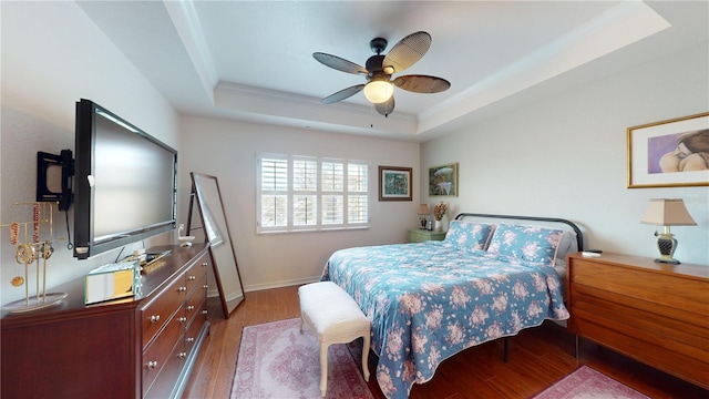 bedroom featuring ceiling fan, light hardwood / wood-style flooring, a tray ceiling, and crown molding