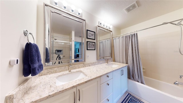 bathroom with a textured ceiling, shower / bathtub combination with curtain, and vanity