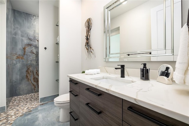 bathroom featuring tiled shower, vanity, and toilet