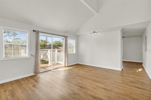 unfurnished room with high vaulted ceiling, rail lighting, and light hardwood / wood-style floors