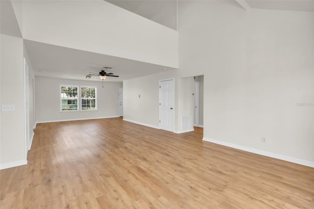 unfurnished living room with a towering ceiling, ceiling fan, and light wood-type flooring