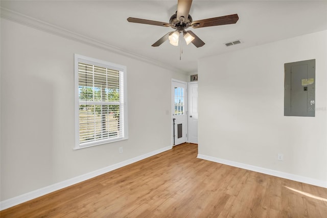 empty room featuring ceiling fan, ornamental molding, electric panel, and light wood-type flooring