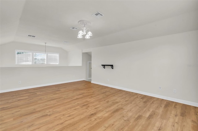 unfurnished room with lofted ceiling, a chandelier, and light hardwood / wood-style flooring