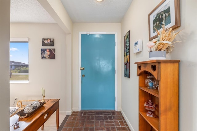 doorway to outside with a textured ceiling