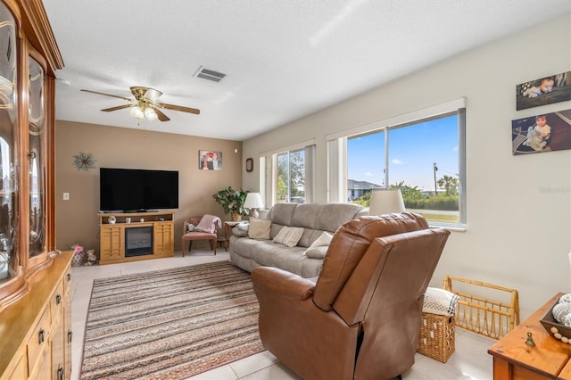 living room with light tile patterned flooring, ceiling fan, and a textured ceiling