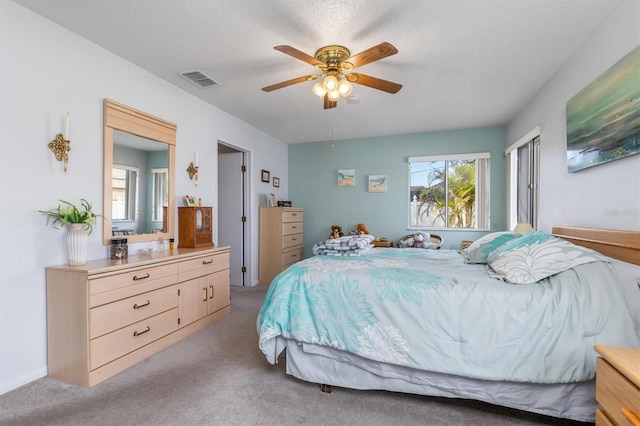 bedroom with a textured ceiling, light colored carpet, and ceiling fan