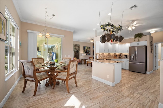 kitchen with pendant lighting, white cabinets, decorative backsplash, stainless steel fridge, and light stone counters