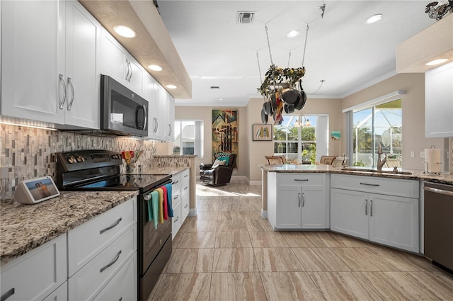 kitchen featuring appliances with stainless steel finishes, white cabinetry, light stone counters, ornamental molding, and decorative backsplash