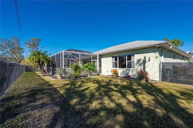 rear view of property with a lanai and a yard