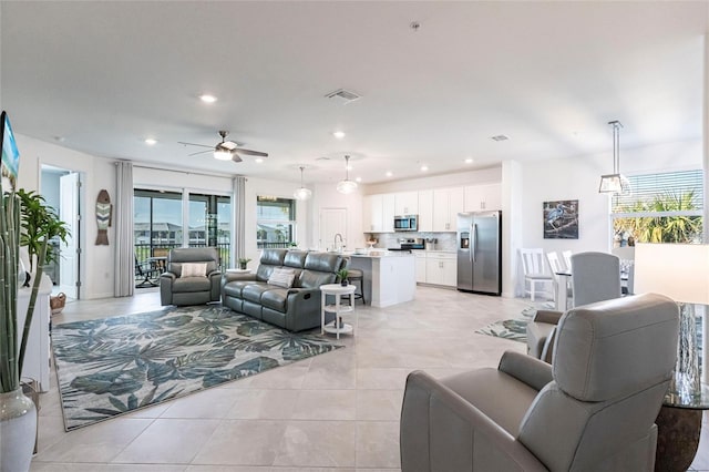 living room featuring sink, ceiling fan, and light tile patterned flooring