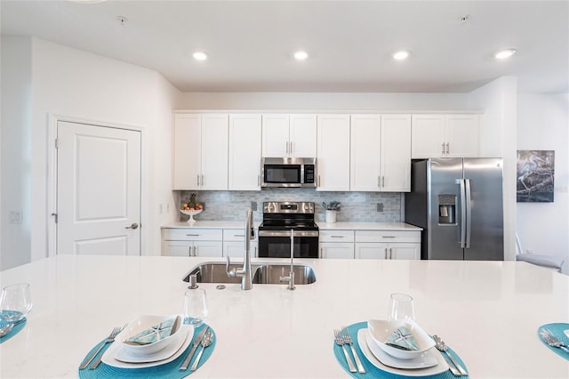 kitchen with white cabinetry, appliances with stainless steel finishes, sink, and backsplash