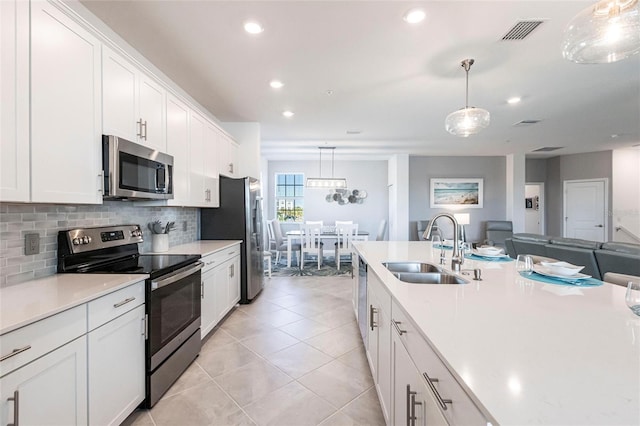 kitchen featuring appliances with stainless steel finishes, sink, white cabinets, and decorative light fixtures