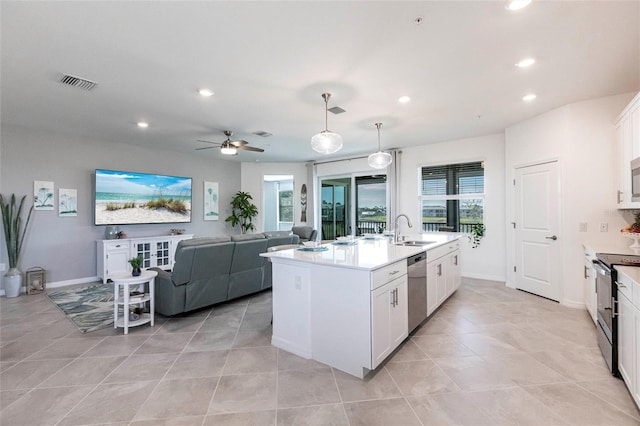 kitchen featuring sink, appliances with stainless steel finishes, a kitchen island with sink, hanging light fixtures, and white cabinets