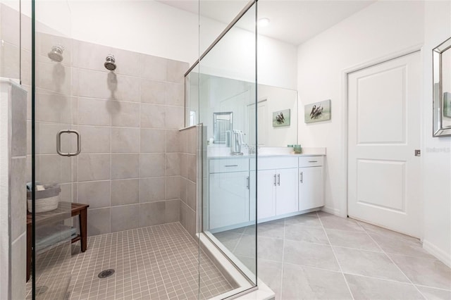 bathroom with a shower with door, vanity, and tile patterned floors